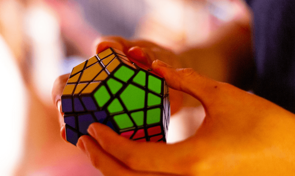 Hands holding a colorful puzzle cube